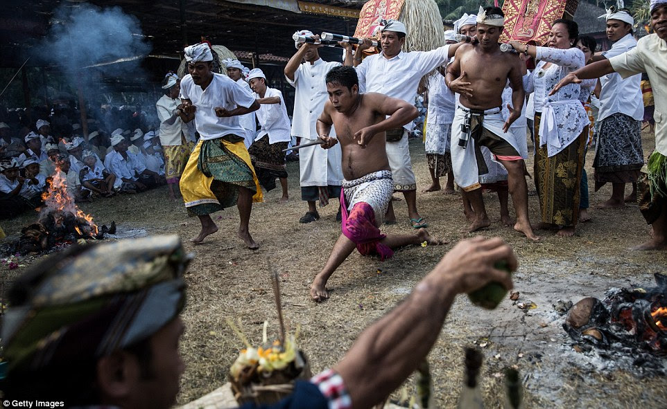 Palanquins, their symbol of God, are carried while men dance with knives, some stabbing themselves in a trance