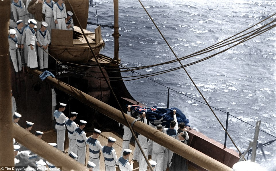 Australian sailors stand looking on as a group hoist the national flag in an image from 'The Digger's View: WWI in Colour' 
