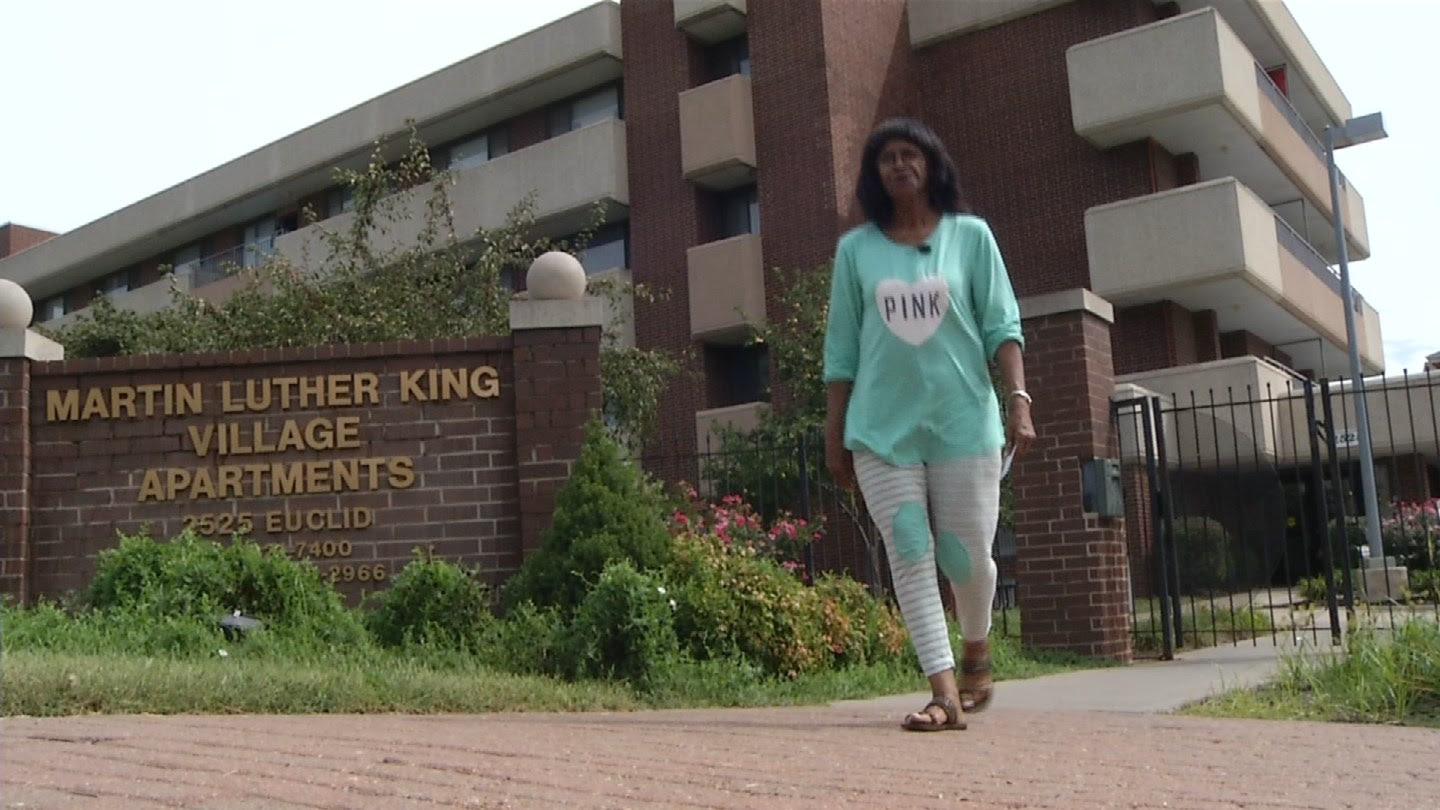 Virginia Dale walks past the sign for Martin Luther King Apartments. (KCTV5)