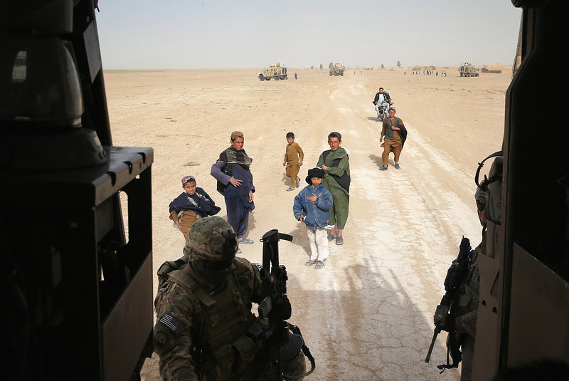 Description of  KANDAHAR, AFGHANISTAN - MARCH 09:  Children watch as soldiers with the U.S. Army's 4th squadron 2d Cavalry Regiment climb back into their MRAP vehicles following a patrol into a village on March 9, 2014 near Kandahar, Afghanistan.  U.S. President Barack Obama recently ordered the Pentagon to begin contingency planning for a pullout from Afghanistan by the end of 2014 if Afghanistan President Hamid Karzai or his successor refuses to sign the Bilateral Security Agreement.  (Photo by Scott Olson/Getty Images)
