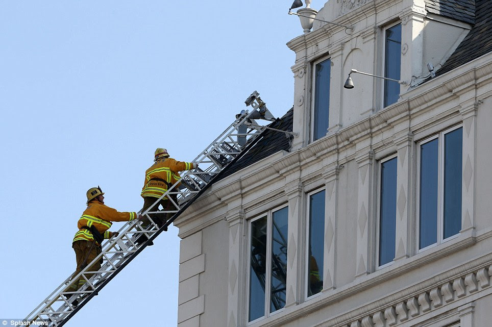 Quick response: Firefighters scale the roof of the complex. They were dispatched at 9.50am and extinguished the flames just after 10am