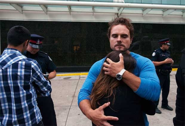 Pessoas se abraçam fora do Eaton Centre em Toronto, Canadá, neste sábado (2) (Foto: Reuters)