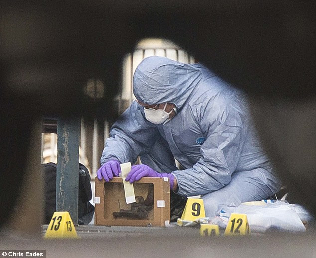Delicate: A forensic officers examine a revolver at the scene and p0laces it in a protective box pistol close to Woolwich Barracks