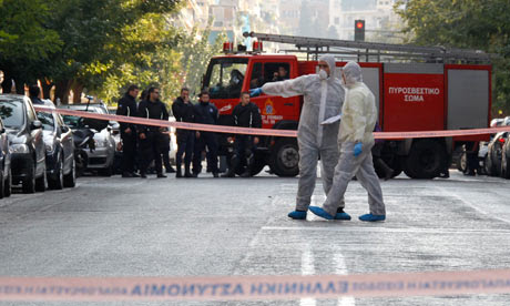 Police search for evidence outside a courier company where a package exploded in Athens