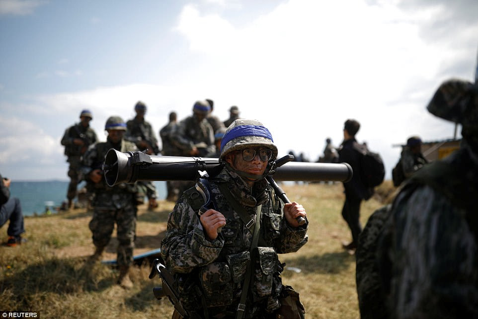 Heavy load: One marine was seen holding a mortar on his back as he came ashore during the annual military excersie