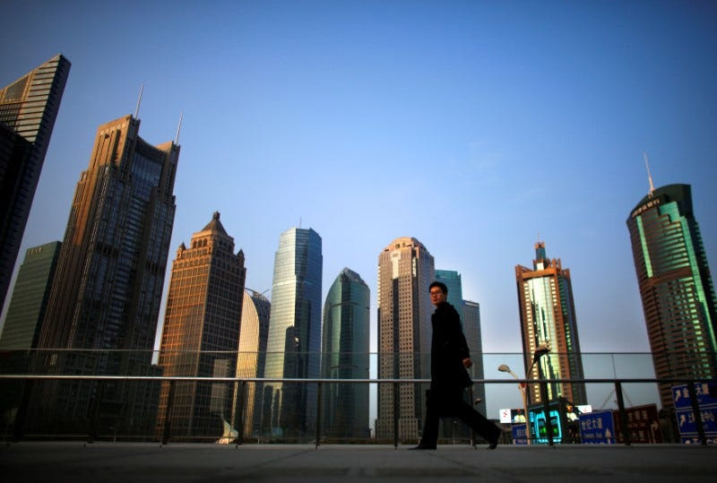 FILE PHOTO: A man walks at the financial district of Pudong in Shanghai March 11, 2014. REUTERS/Carlos Barria/File Photo 