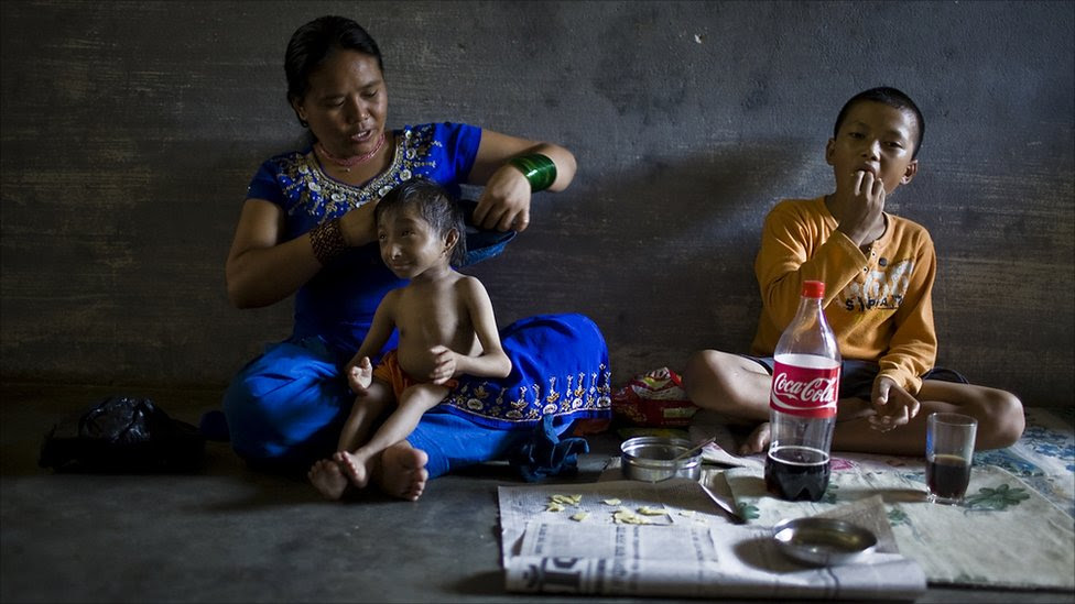 Dhana Maya helps her son, Khagendra Thapa Magar, change out of his clothes after school (Photo by Tom van Cakenberghe)
