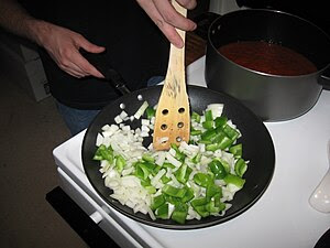 A cook sautees onions and peppers.