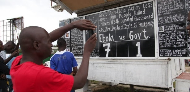 Homem fotografa placa que indica situação do surto de ebola em Monróvia, na Libéria