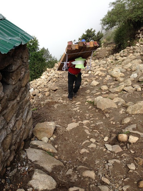 A Sherpa man and his heavy load on the Everest Base Camp trail