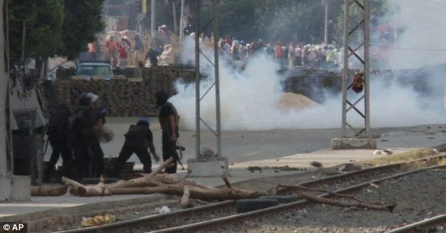 Action: Protestors can be seen behind a barricade in the background as tear gas is fired at protestors earlier today