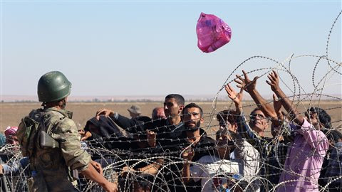 Un soldat turc lance un sac rempli de bouteilles deau  un groupe de 