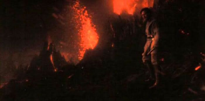 Obi-Wan picks Anakin's lightsaber up from the black sand.