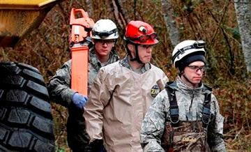 (AP Photo/Elaine Thompson, Pool). Searchers walk past heavy equipment as they leave the scene of a deadly mudslide, Saturday, March 29, 2014, in Oso, Wash.