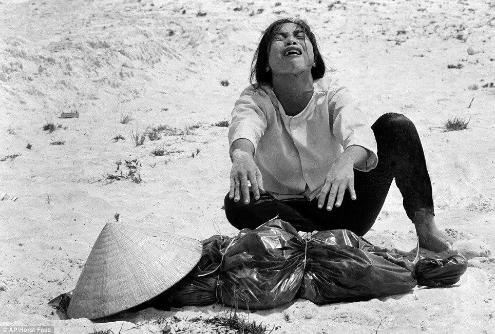 Poignant: A South Vietnamese woman mourns over the body of her husband, found with 47 others in a mass grave near Hue, Vietnam in April 1969