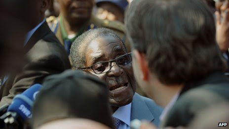 Robert Mugabe (C) answers journalists questions after voting at a polling station at a school in Harare on 31 July