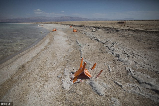 The sea's surface and shores are 1,407ft (429 metres) below sea level, making the Dead Sea the Earth's lowest elevation on land. This image shows a chair covered with salt sticking out of the sand at the coastal resort near Ein Gedi, where water levels are being monitored