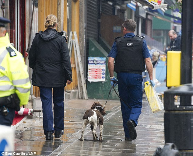 A sniffer dog is used to search for evidence at the scene of the double shooting. No arrests have been made