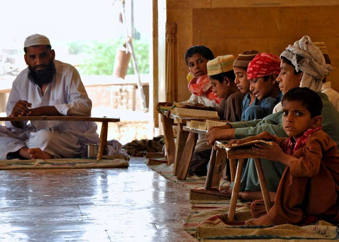 A Qari at the Derawar Mosque giving lessons on how to read the Quran to
children from the neighbouring village. The children keep their copies of the
Quran on small, primitive wooden stools.