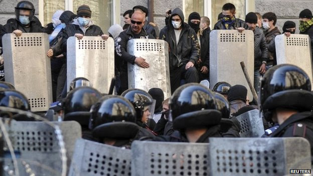 Pro-Russian protesters (top) stand in front of riot police near the regional government building in Donetsk April 6, 2014