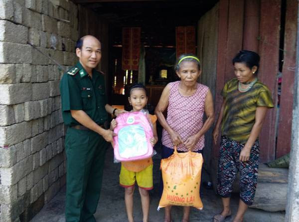  Đại uý Nguyễn Văn Vỹ (người đứng ngoài cùng bên trái ảnh) tặng cặp sách, gạo cho học trò và gia đình. Anh hiện đang đỡ đầu cho 3 học sinh nghèo để các em có điều kiện cắp sách tới trườn