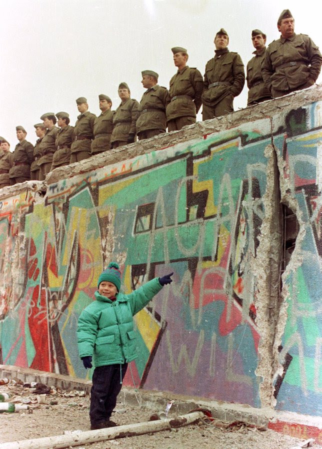 Una niña señala un agujero en el Muro bajo los gua