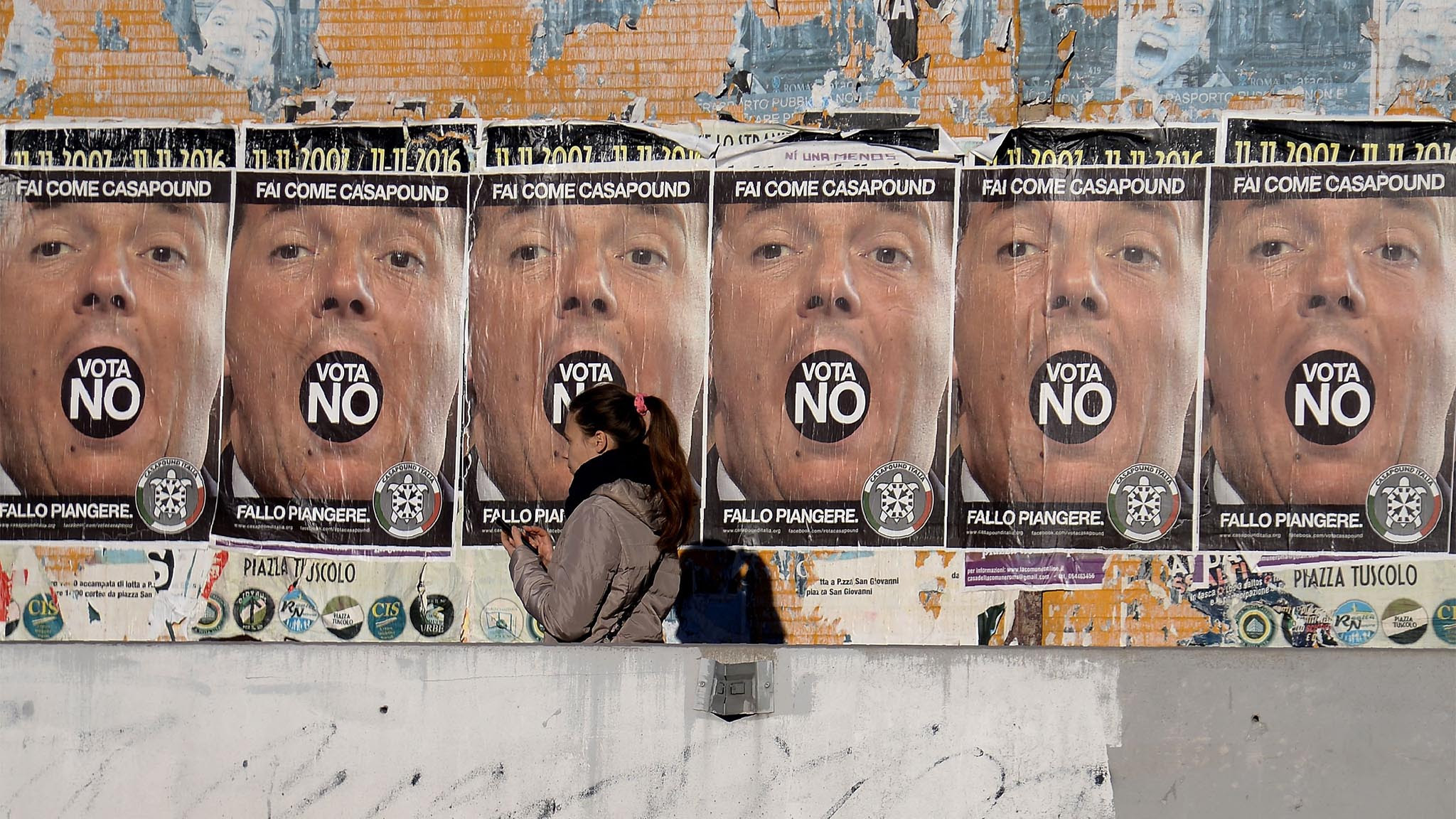 A woman walks past posters from the far-right political movement Casapound