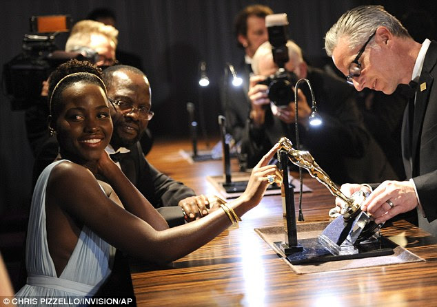 Engraved: Lupita Nyong'o watches as her statue is sketched at the Governors Ball after the Oscars on Sunday