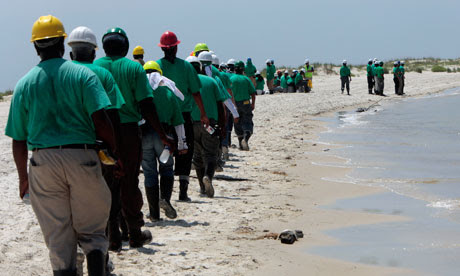 Oil cleanup workers hired by BP walk along the beach in Dauphin Island