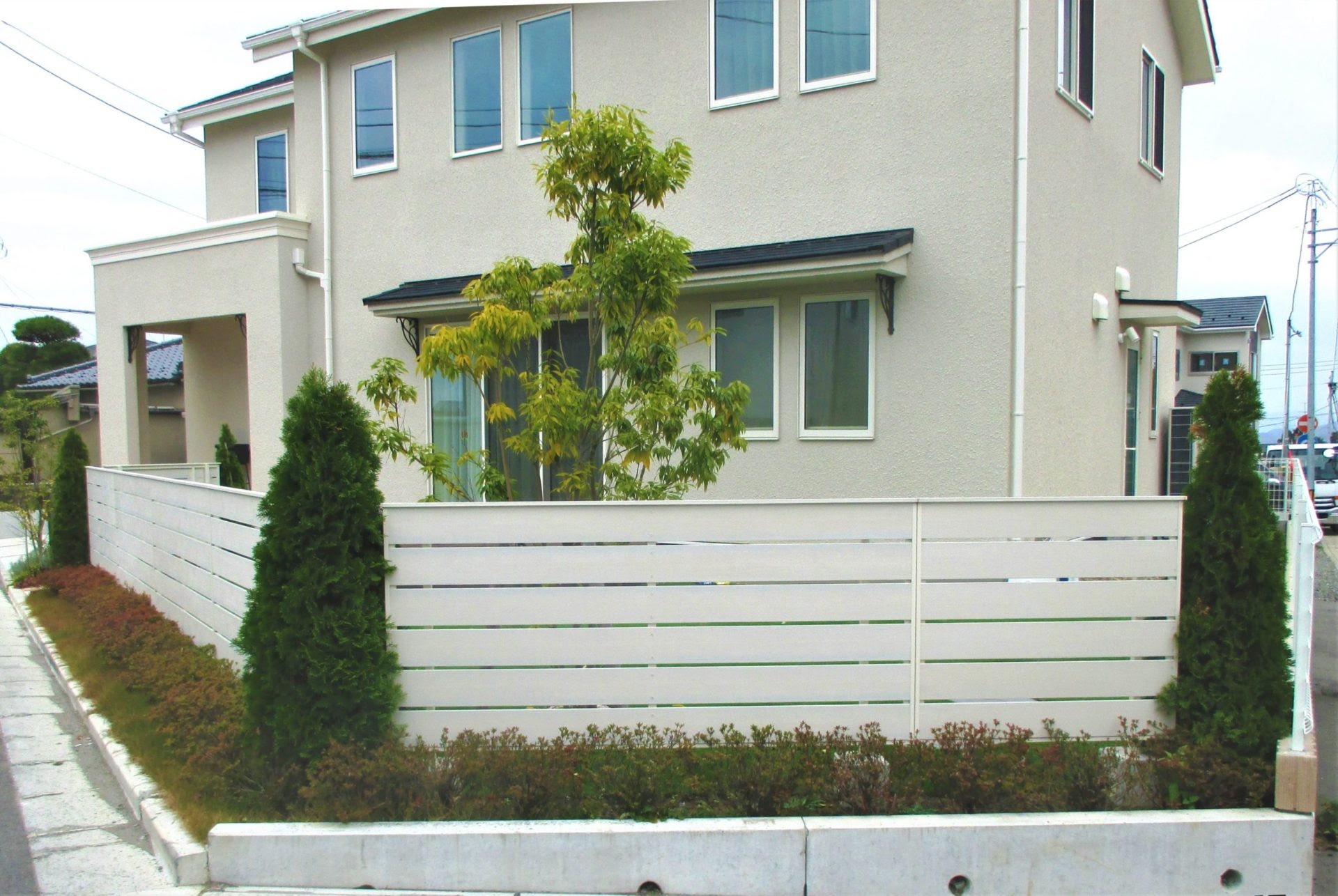 外壁と合わせたホワイトの目隠しフェンスとコニファーの組合せ 仙台の外構工事 エクステリア お庭のリフォーム 泉ホームイング