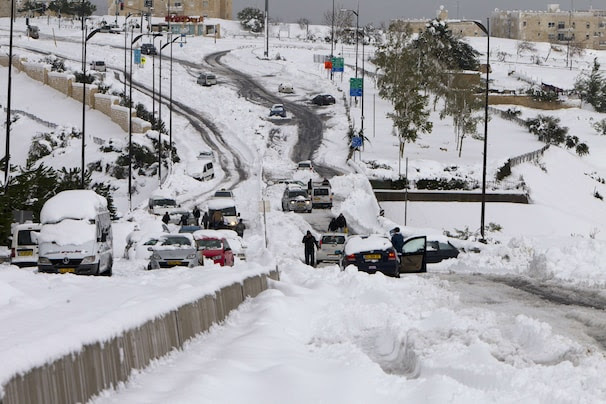 Vehicles are see stranded in the snow in Jerusalem on December 13, 2013. AFP PHOTO/AHMAD GHARABLI