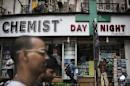 People walk past a chemist shop at a market in Mumbai