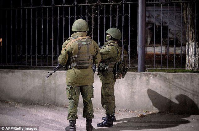 Armed members of the Russian forces wait outside as Ukrainian soldiers stand guard inside the Ukrainian Navy headquarters in Simferopol. Previously the Ukrainian forces had been told not to fire at advancing Russian forces, but have now been given the go-ahead for armed self-defence