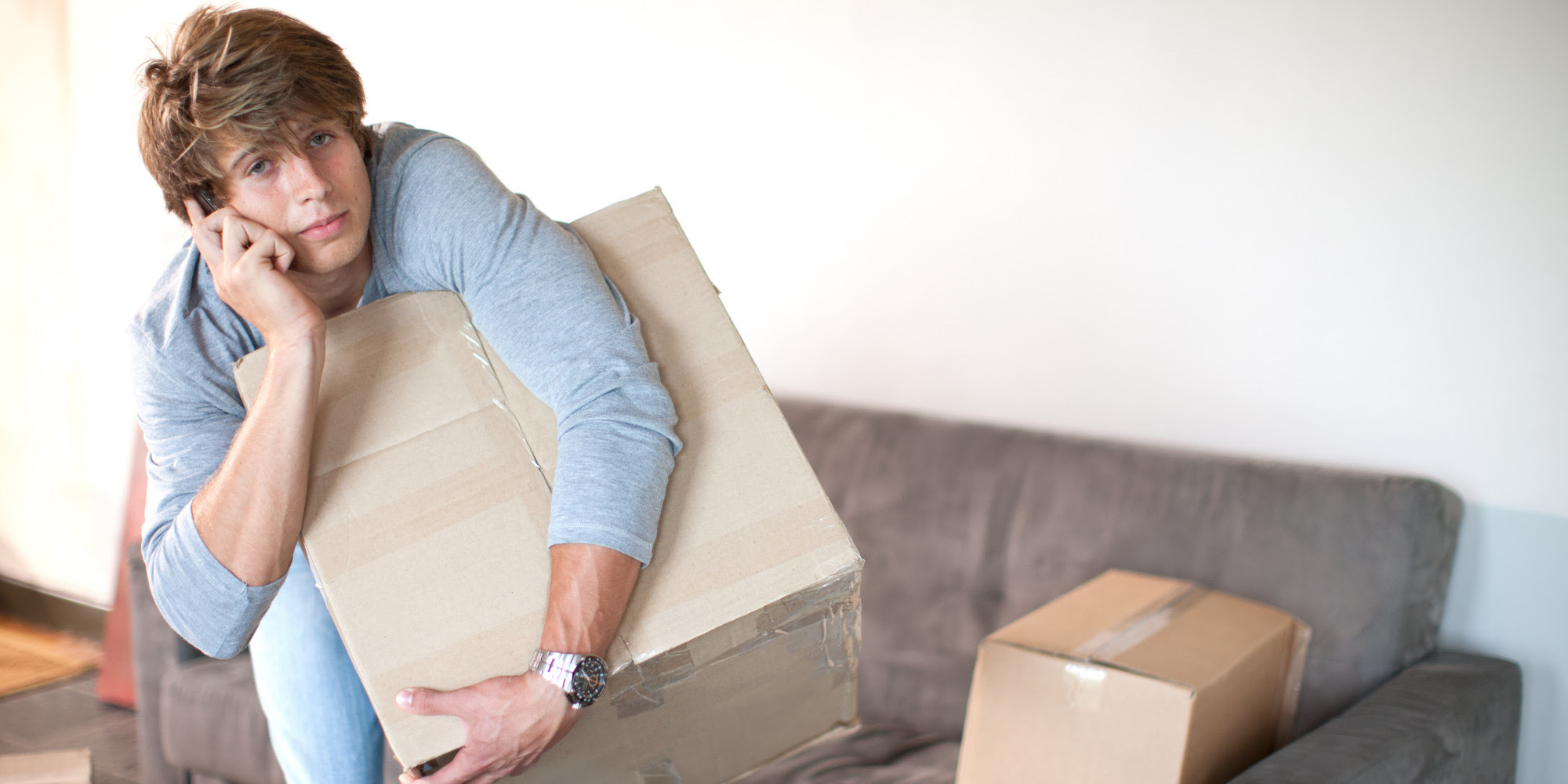 image of a man holding a box in the sofa