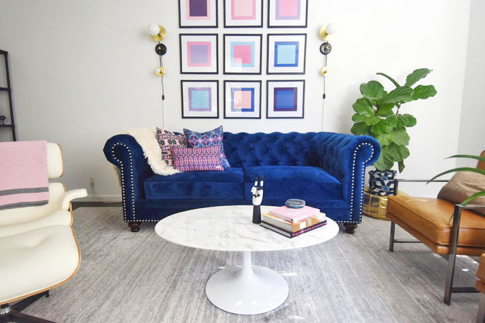 Midcentury glam living room, navy chesterfield sofa, saarinen tulip table, pop art, pink and blue, eames lounge chair