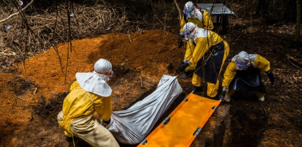 Equipe funerária enterra o corpo de um homem que morreu após contrair vírus ebola na Libéria