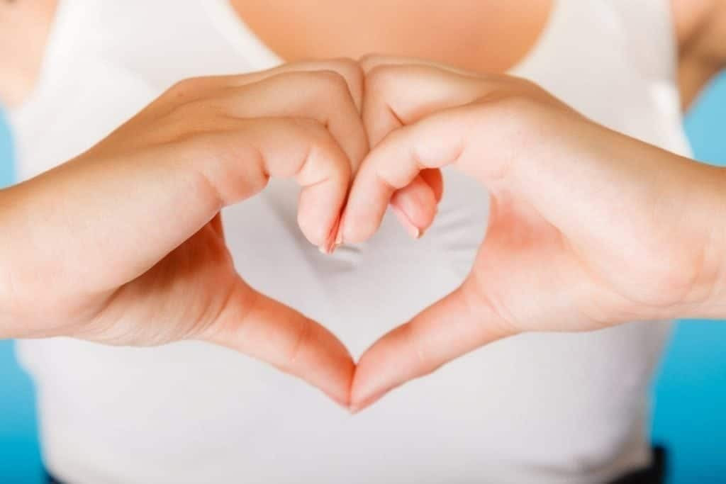 Love, hope and charity concept. Woman hands creating heart sign symbol on blue background. Studio shot.