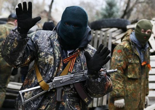 An armed man gestures in front of the police headquarters in Slaviansk, April 12, 2014. REUTERS-Gleb Garanich