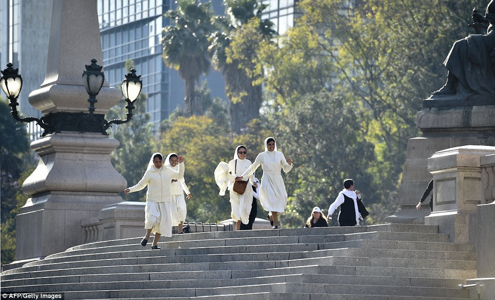 A group of nuns run down the steps in Independence Square in Mexico City in a bid to catch a glimpse of Pope Francis, who is visiting the city 