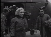 Marilyn Monroe steps down from US military helicopter before getting into car and posing with officer during tour of military bases, Korea; Feb 54