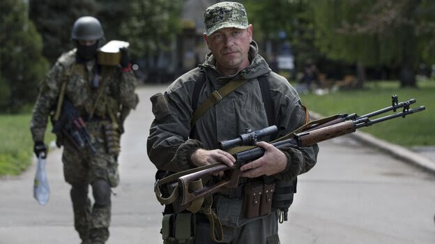 Pro-Russian gunmen carry their weapons in the center of Slovyansk, Ukraine, Tuesday. Gun battles were fought around the city Monday in what has proven the most ambitious government effort to regain control of areas taken by separatists.