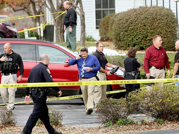 Policiais de Davenport e Bettendorf vistoriam estacionamento onde homem se matou com um tiro, na segunda (26) (Foto: Jeff Cook/Quad City Times via AP)
