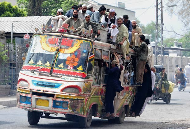 Em 10 de abril de 2012, um ônibus foi flagrado superlotado em Peshawar, no Paquistão. Em cima do teto, viajavam pelo menos 15 pessoas. Outras estavam agarradas às laterais do ônibus. (Foto: A. Majeed/AFP)