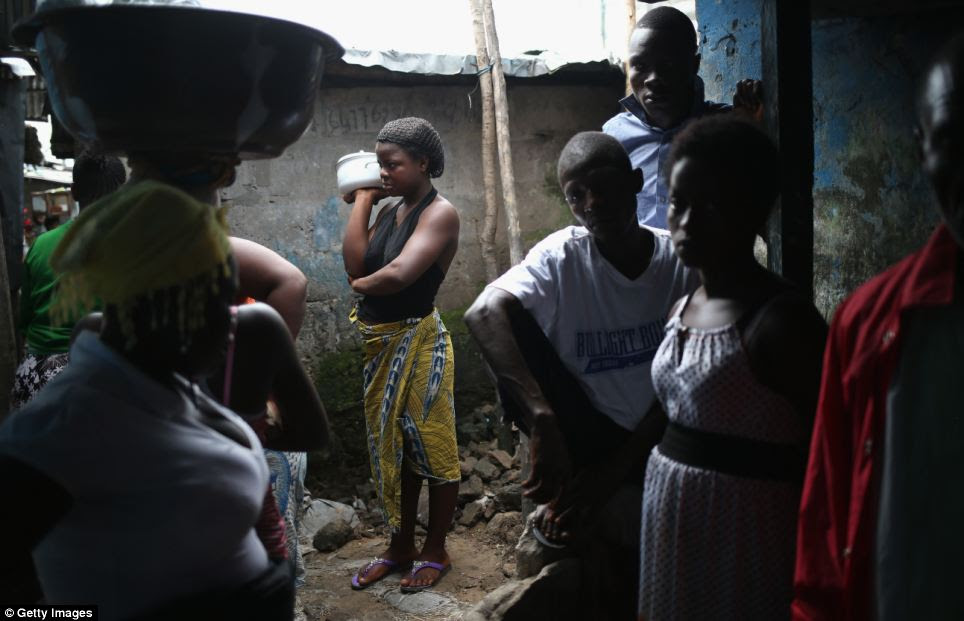Residents stand outside the home of a person sick with Ebola in West Point