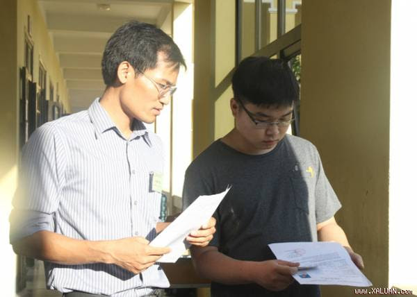 Giám thị kiểm tra thẻ dự thi của thí sinh trước khi vào phòng thi tại điểm thi Trường THPT Lê Viết Thuật (Nghệ An) sáng nay.