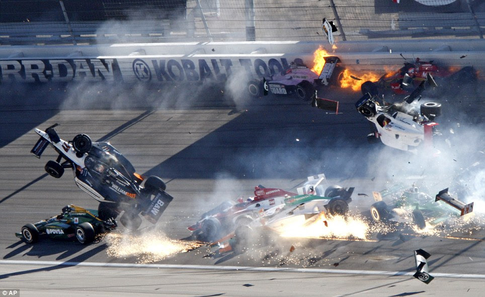 Tragedy: Dan Wheldon's number 77 car, far left, launches into the air after clipping a vehicle that was in front of it. Moments later Mr Wheldon smashes into the fencing to his right