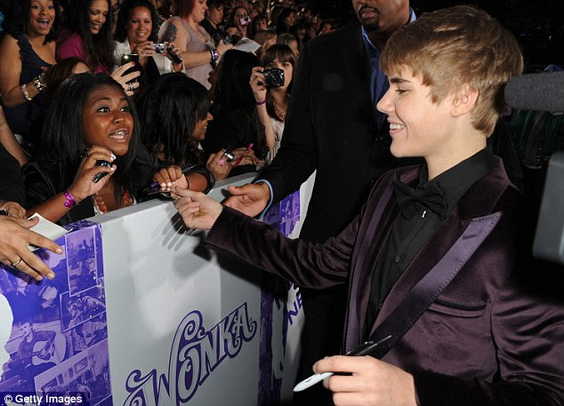 Bieber fever: The pint-sized pop star signs autographs for his adoring fans who arrived at the Nokia Theatre in Downtown Los Angeles