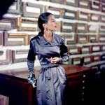 1947 --- Fashion model Sabine wears a silver evening dress by Pauline Trigere on a framing shop's stairway. --- Image by © Genevieve Naylor/Corbis
