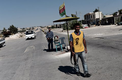 A Kurdish man wearing a T-shirt with the portrait of Abdullah Ocalan, the jailed PKK leader, guards a checkpoint near the Syrian-Turkish border.