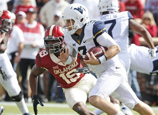West Virginia quarterback Skyler Howard (3) runs past Oklahoma linebacker Eric Striker (19) in the first quarter of an NCAA college football game in Norman, Okla., Saturday, Oct. 3, 2015. (AP Photo/Sue Ogrocki)